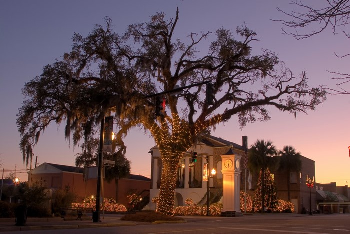 Town square with decorated tree and clock tower at dusk