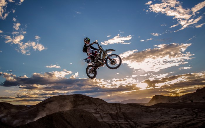 Motocross rider jumping against a cloudy sky