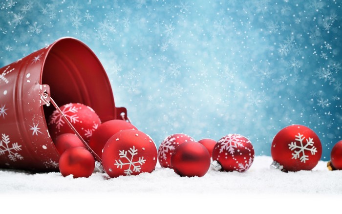 Christmas ornaments spilling from a red bucket in the snow