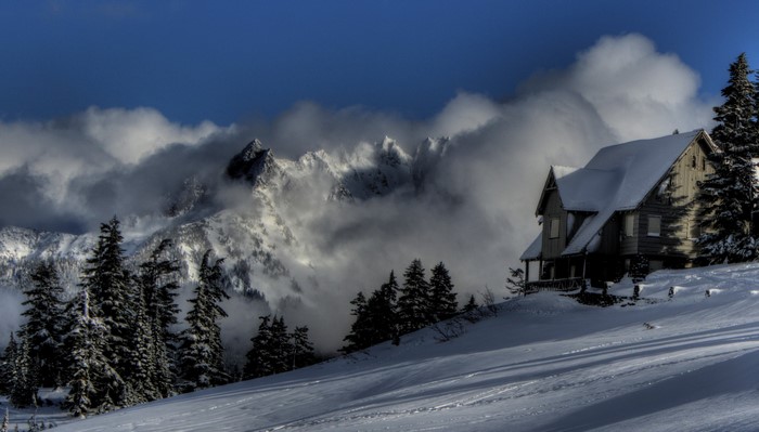 Snowy cabin in the mountains with clouds