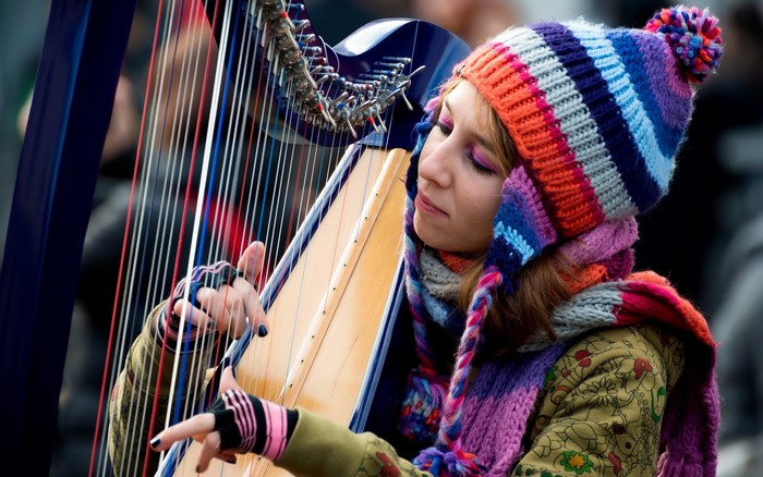 Woman playing a harp wearing a winter hat