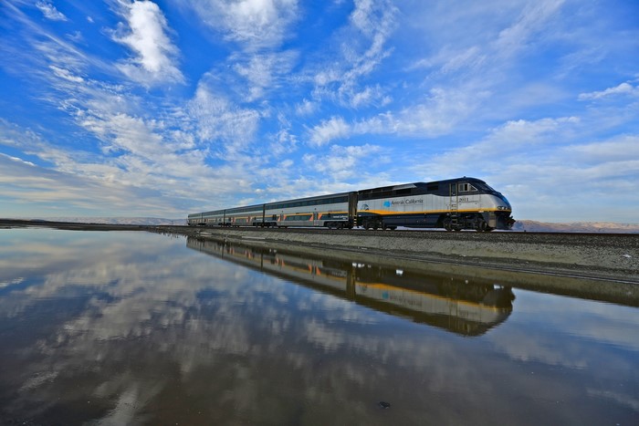 Amtrak California train reflected in water under a cloudy sky
