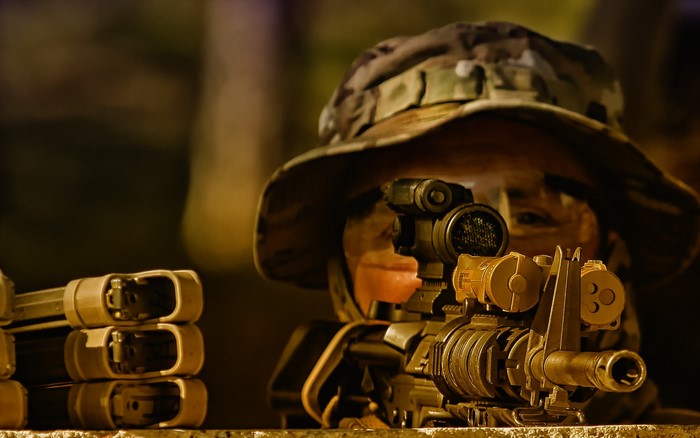 Soldier aiming an assault rifle with magazines