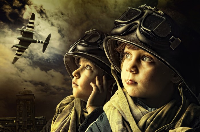Two children in helmets and goggles looking at a plane