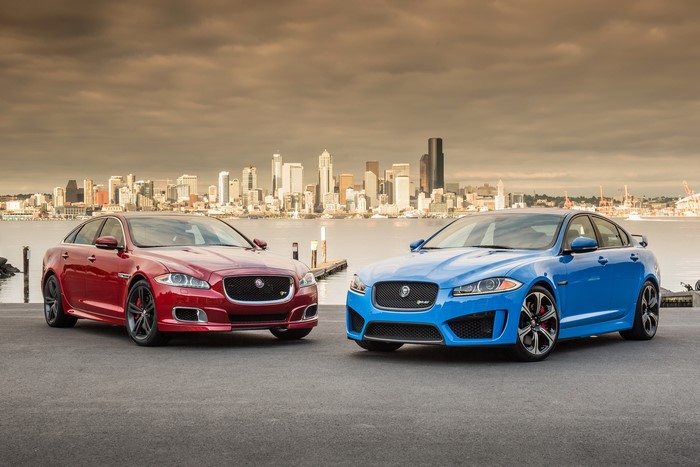 Two Jaguar sedans in front of a city skyline