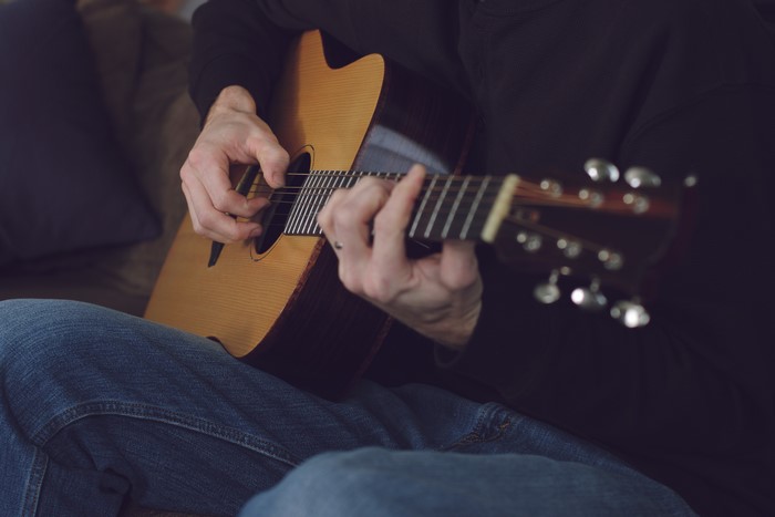 Man playing acoustic guitar in jeans