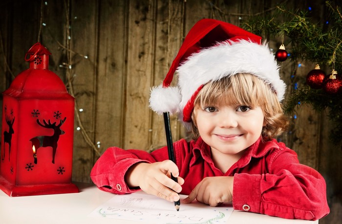 Boy in Santa hat writing a letter to Santa