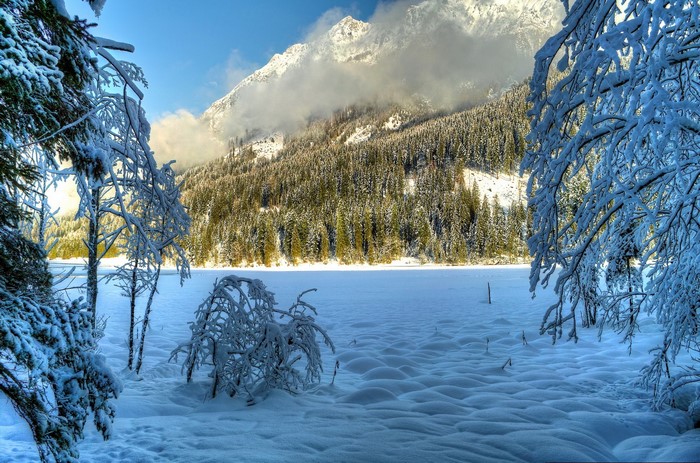Snowy mountain landscape with snow-covered trees and frozen lake