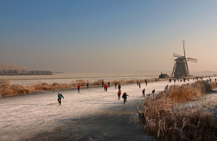People ice skating near a windmill in the Netherlands