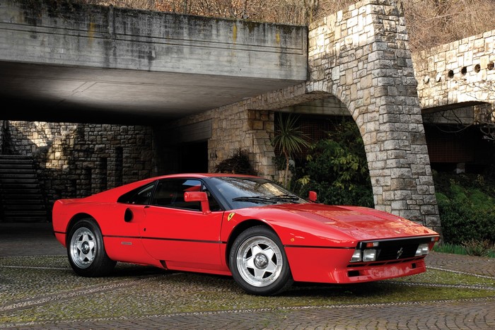 Red Ferrari 288 GTO parked under a stone archway