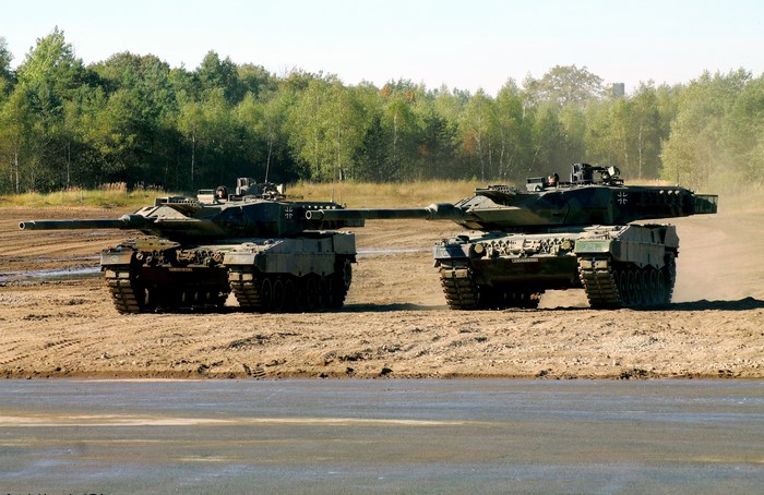 Two Leopard 2A6 tanks on a dirt field