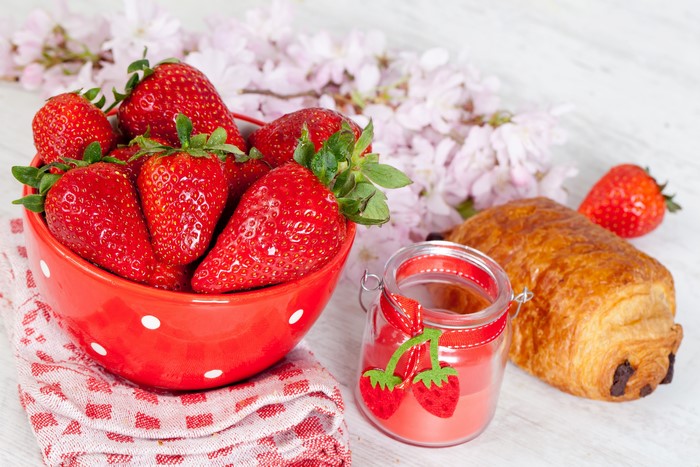 Strawberries in a bowl with a pastry and jam jar