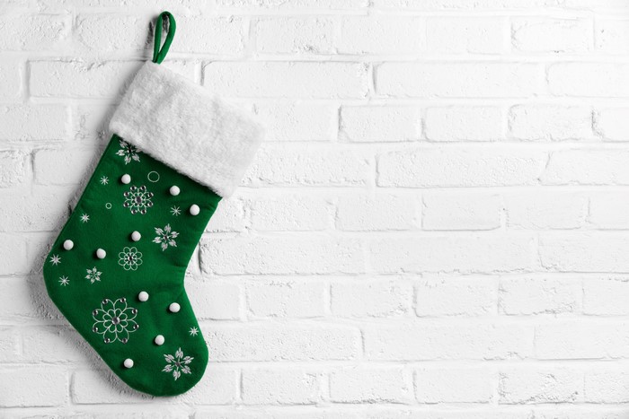 Green Christmas stocking with snowflakes on a white brick wall
