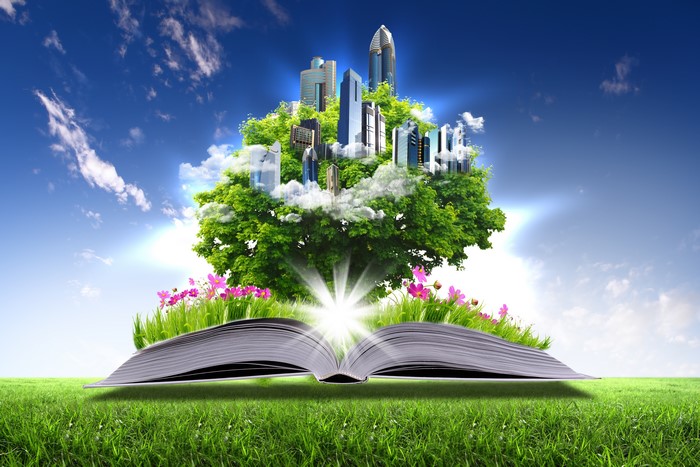 Open book with city on tree and flowers