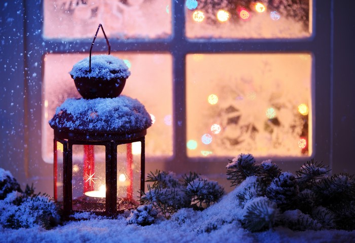 Christmas lantern with snow and lights on window