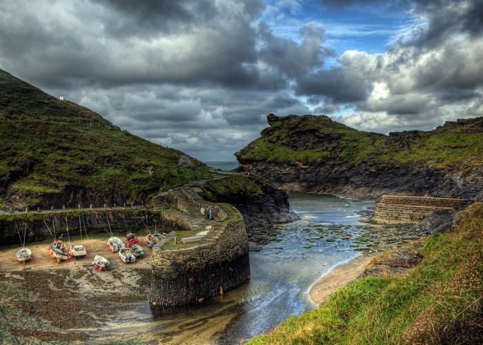 Boats docked in a rocky cove in England under a cloudy sky