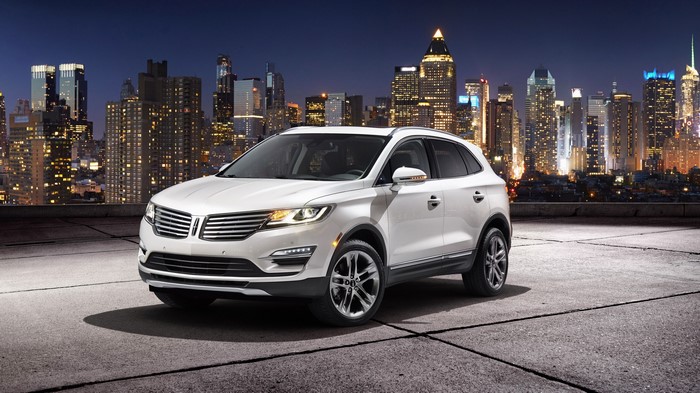 White Lincoln MKC parked in front of a city skyline at night