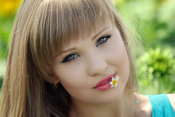 Young woman with a daisy in her mouth