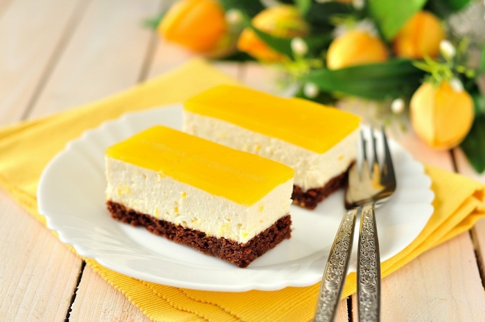 Two slices of lemon cheesecake on a plate with forks
