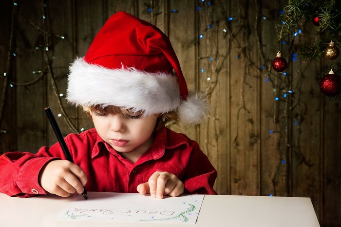 Boy in Santa hat writing a letter to Santa