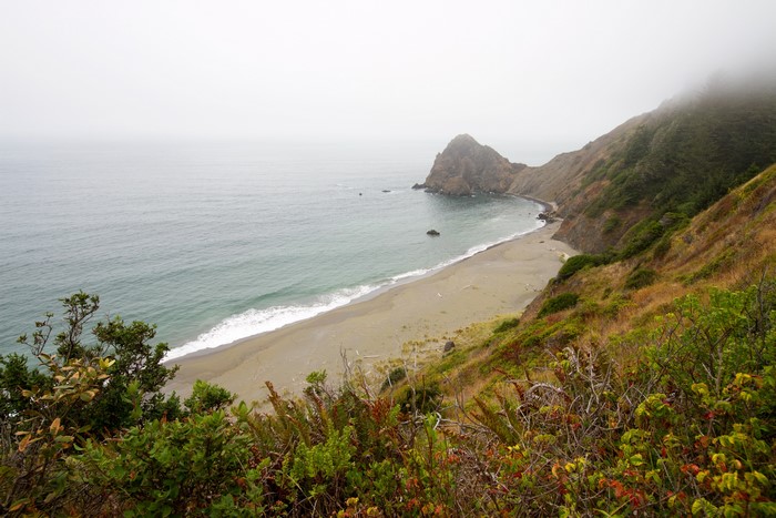 Misty Coastline with Beach and Rocky Outcrop