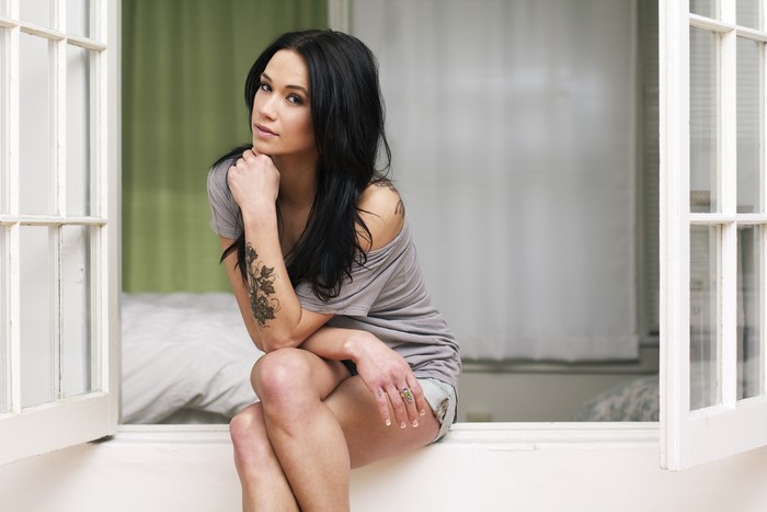 Megan Lyn with tattoos sitting by a window