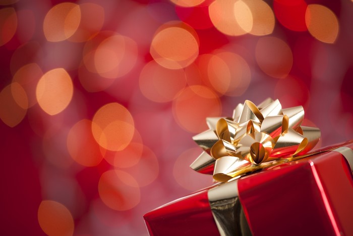 Red gift box with gold bow and bokeh lights