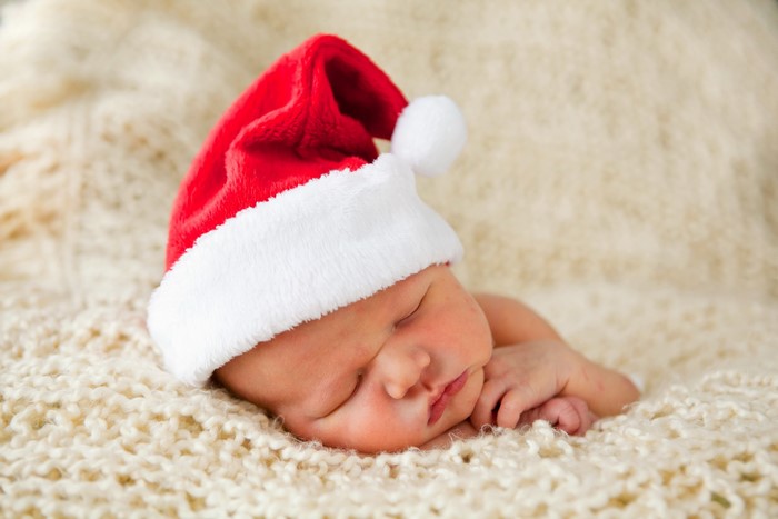 Baby wearing a Santa hat sleeping on a blanket