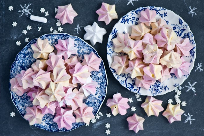 Pink and yellow star-shaped meringues on blue and white plates