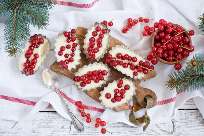 Small tarts with cream and red currants on a wooden board