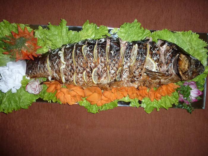 Whole roasted fish with lemon slices and lettuce garnish