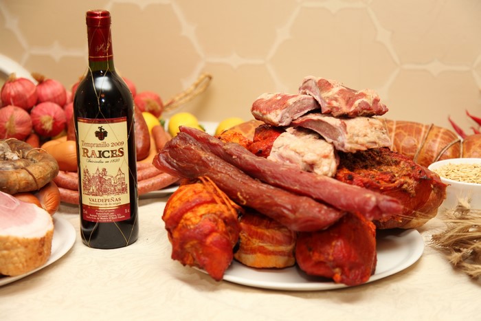 Bottle of Raices Valdepenas wine with assorted meats and sausages