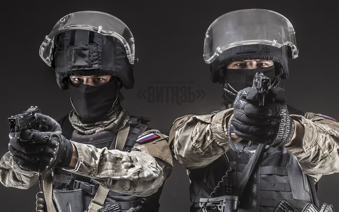 Two soldiers in tactical gear aiming pistols