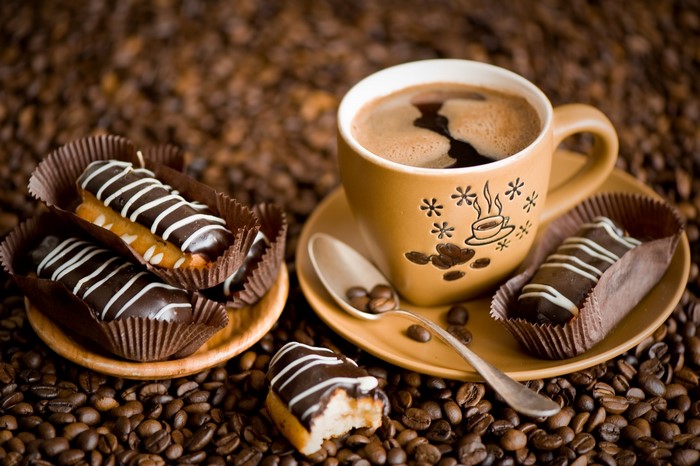 Coffee cup with eclairs and coffee beans