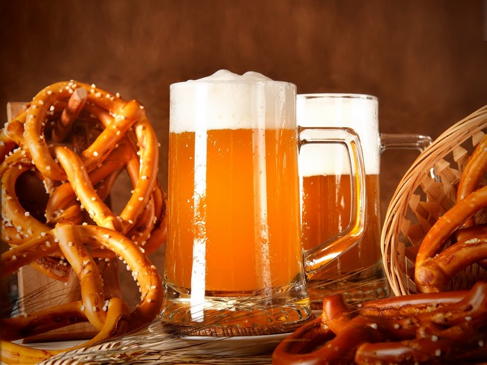 Two mugs of beer with pretzels