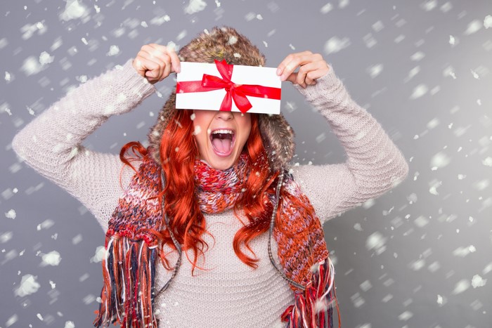 Woman in winter hat and scarf holding gift