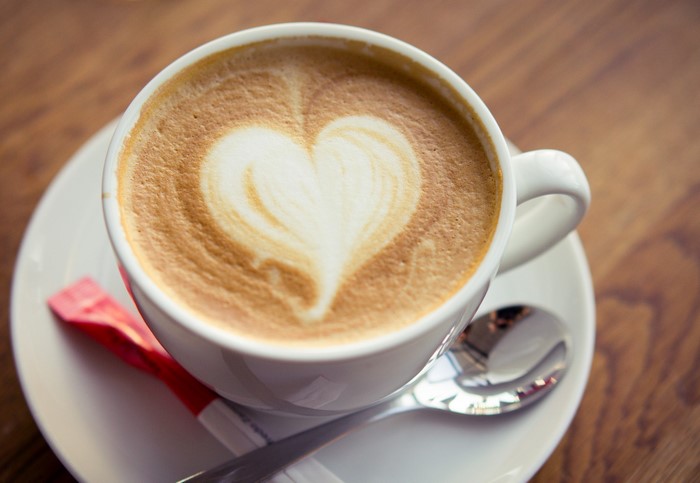 Cappuccino with heart art on a saucer with spoon
