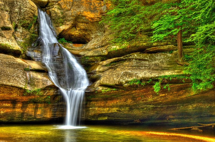 Waterfall cascading over layered rocks into a pool