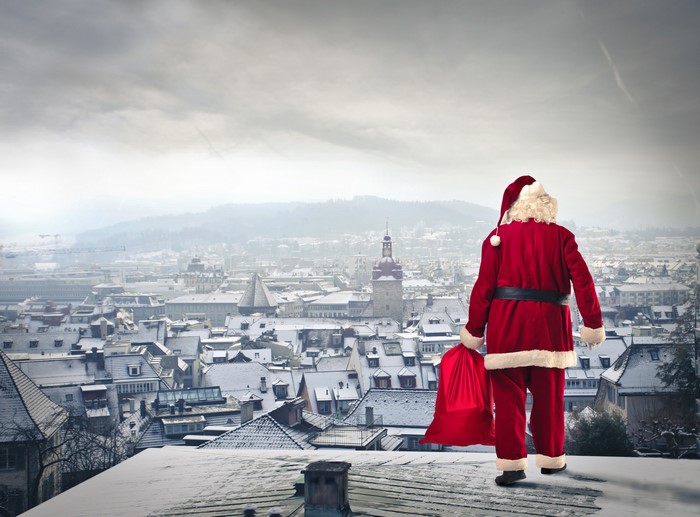 Santa Claus with a gift bag overlooking a snowy city