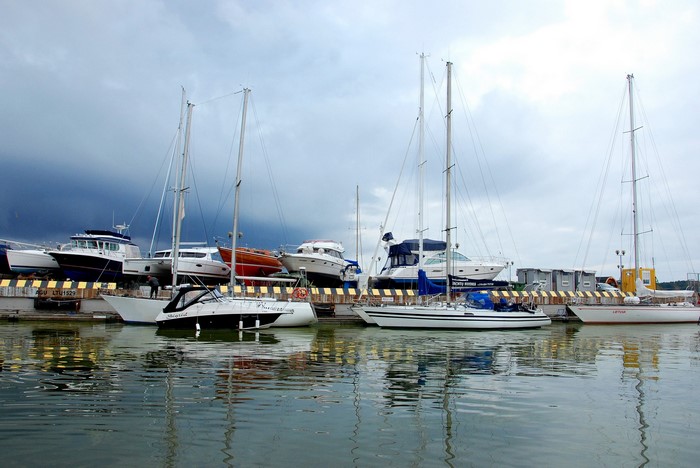 Boats and yachts docked in a harbor under cloudy skies