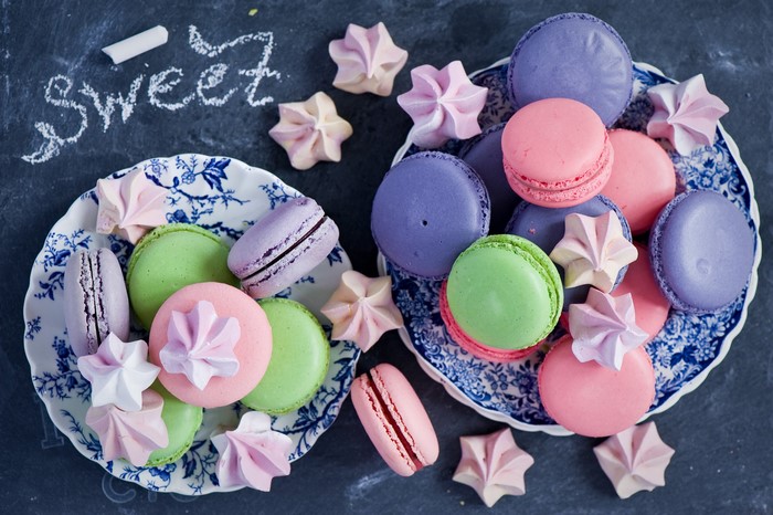 Colorful macarons and meringues on plates
