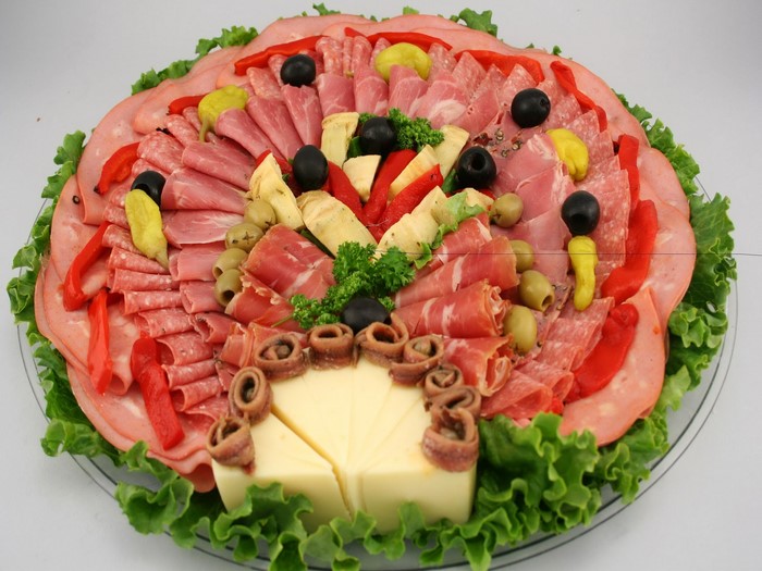 Charcuterie board with meats, cheese, olives, and peppers