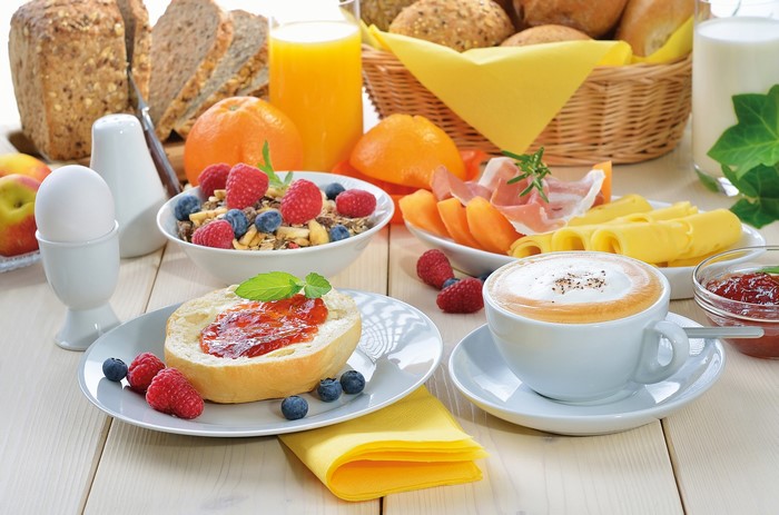 Breakfast spread with coffee, bread, fruit, and muesli