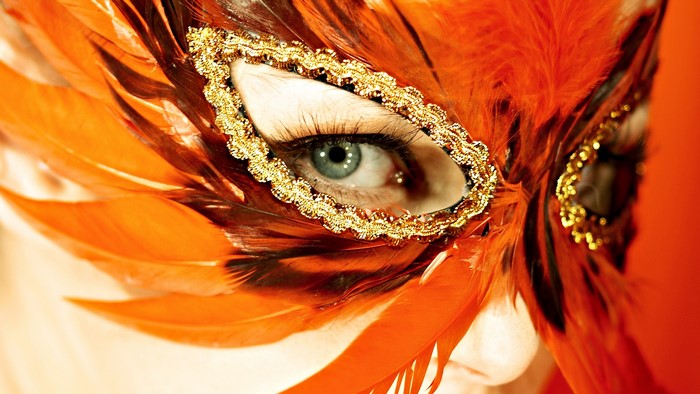 Close-up of a woman wearing an orange feathered mask