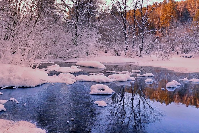 Winter river with snow-covered trees and reflections