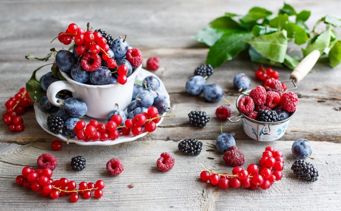 Berries and plums in a cup and bowl