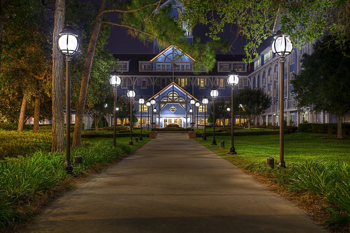 Pathway to blue building with street lights at night