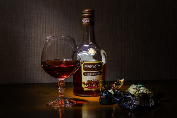 Brandy bottle and glass with chocolates