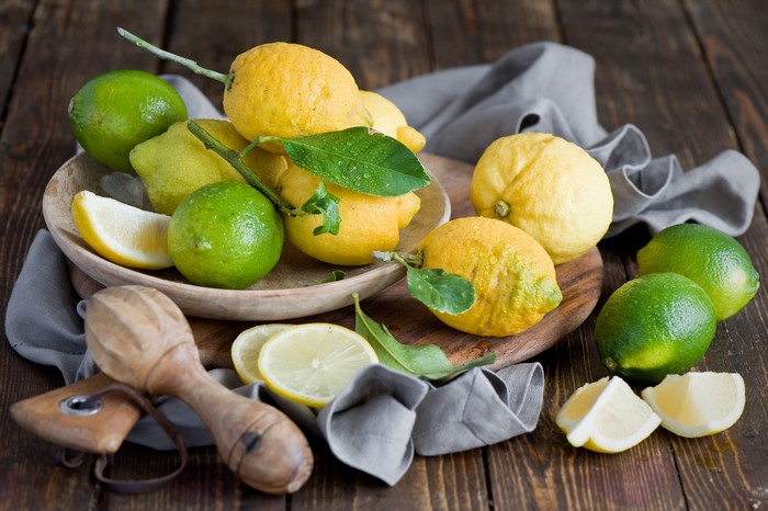 Lemons and limes with a wooden juicer