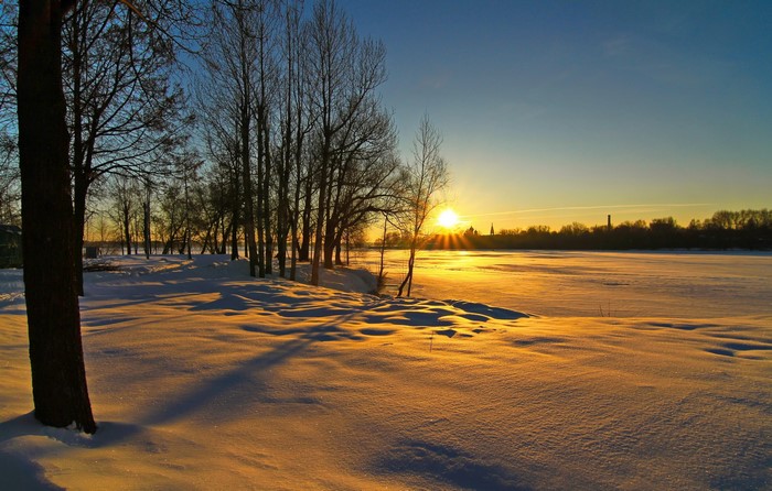 Winter sunset over a snowy landscape with trees